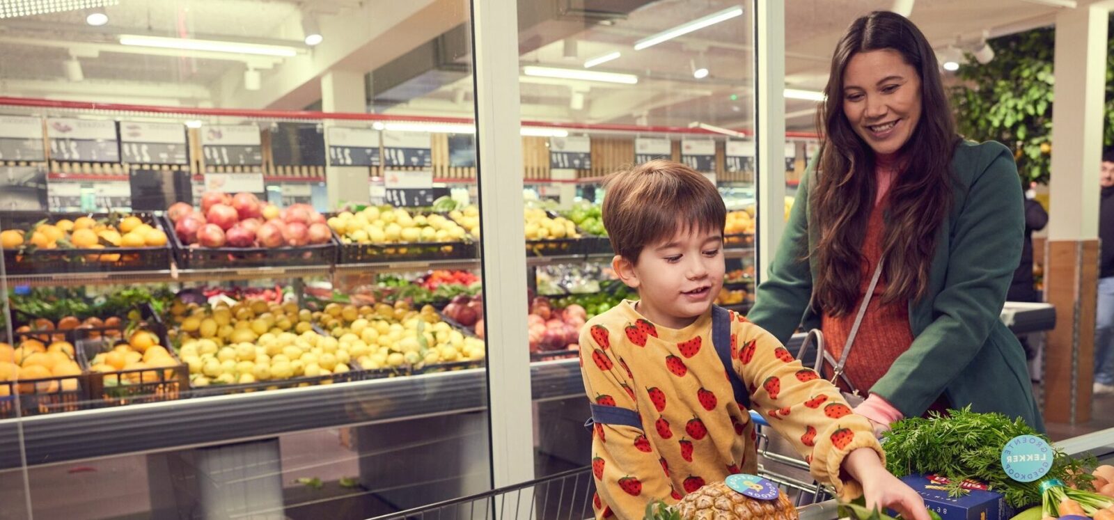 Moeder en kind in de supermarkt bij de kassa om gezonde producten af te rekenen.